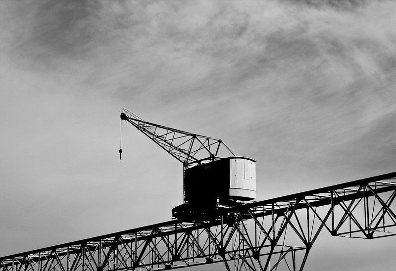 Black and White photo of a docker crane on rails elevated above the ground.